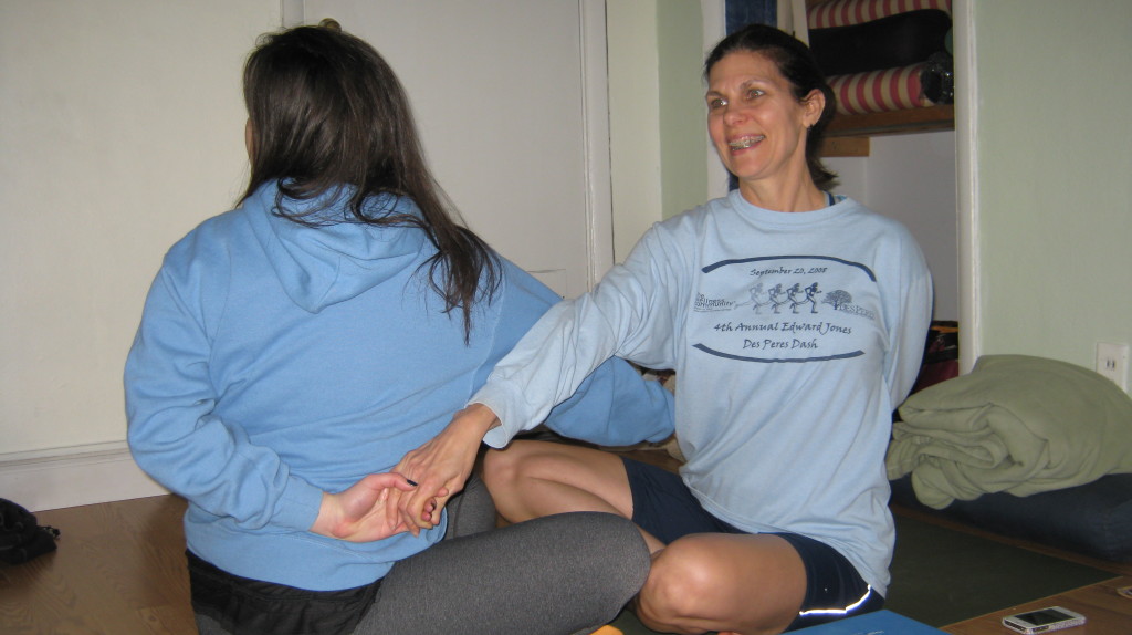 From a seated posture of JOY, reach for your partners right hand with your left and look in the same direction as the rotating shoulder.  In all twists, you want to lengthen the spine and soften the shoulders down.