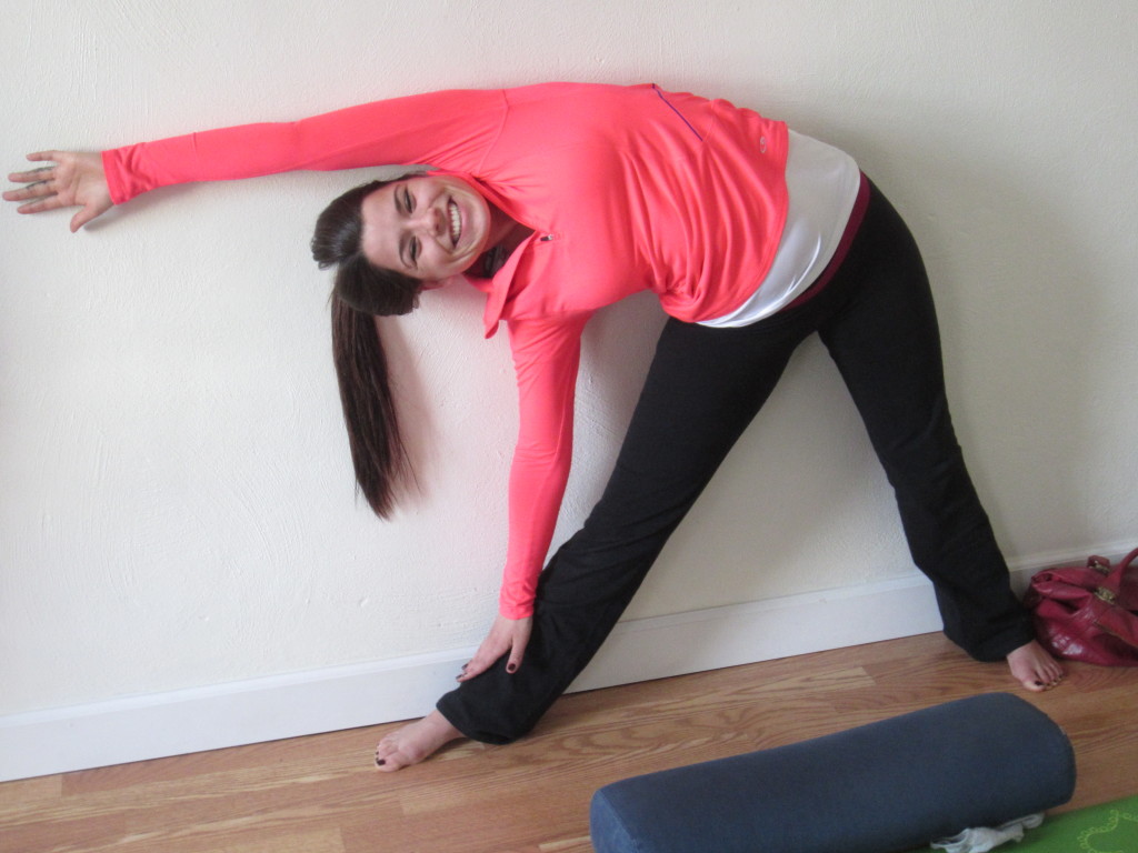 I love this picture!  There is certainly more flexibility and range of motion in her hips than most and she is so happy! In this photo, we see triangle practiced against a wall.  Keep your front knee slightly bent to begin, then shift your body weight forward and hinge from the hip.  Try to pin as many places on the entire back body against the wall as is possible. The use a block under the front hand or even the back of a chair can be most helpful when also establishing that nice long parallel and even side body and rib cage!  You GLOW girl.