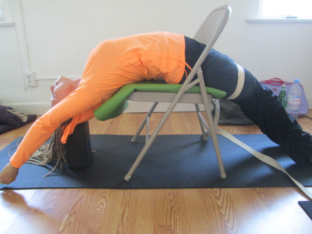 Chair Assisted Backbend with Strap and Block Modification: Work with a partner to provide additional props as needed. Benefits:Flushing body toxins from circulation and lymphatic system Energizing Heart Opening